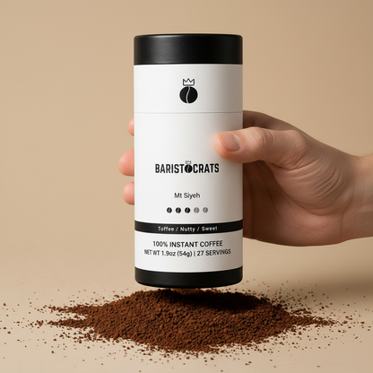 Hand holding Baristocrats Mt Siyeh canister with coffee powder spilled on surface